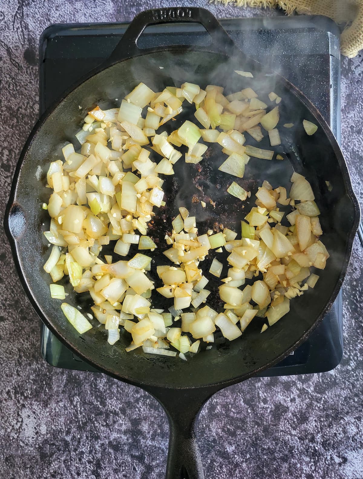 diced onions and minced garlic in a cast iron skillet on a burner