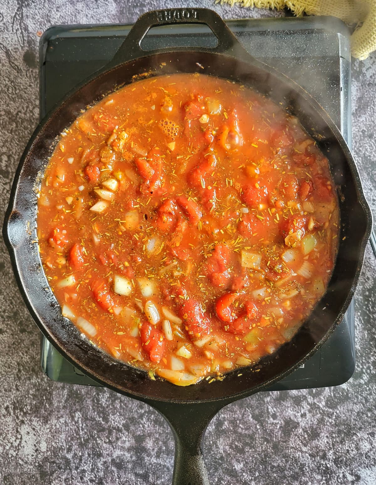 chunky tomato sauce with diced onions and seasonings steaming away in a cast iron skillet