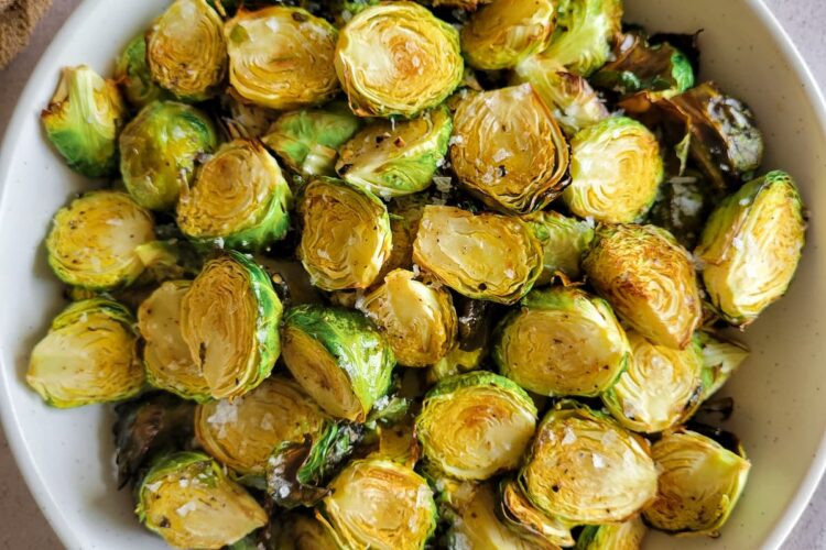bowl of crispy brussels sprouts garnished with flakey sea salt