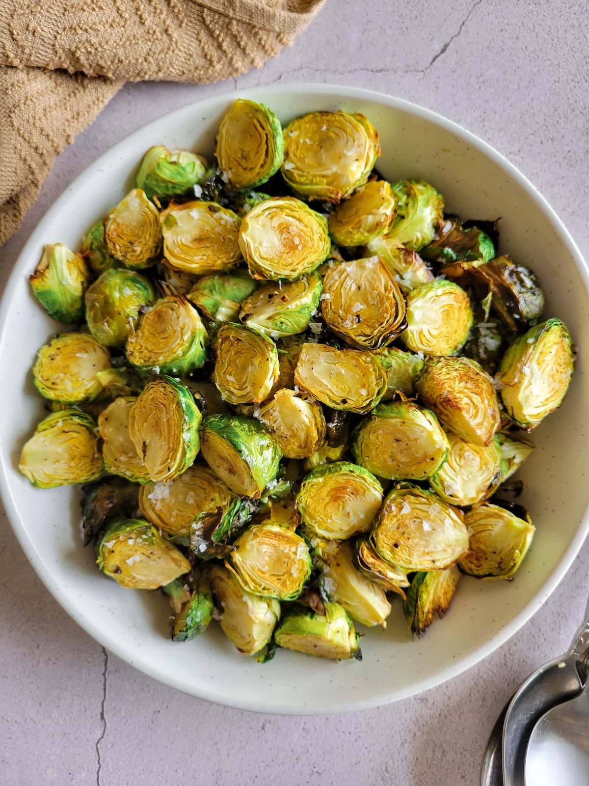 bowl of crispy brussels sprouts garnished with flakey sea salt
