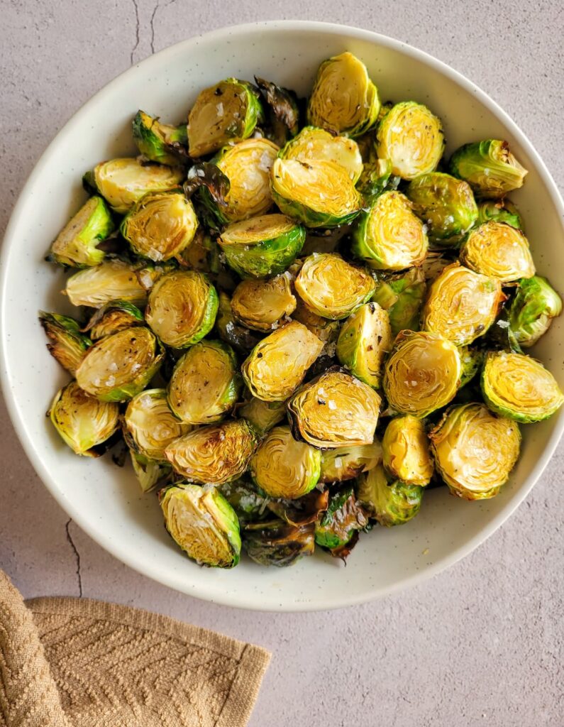 air fried brussels sprouts garnished with flakey sea salt in a bowl