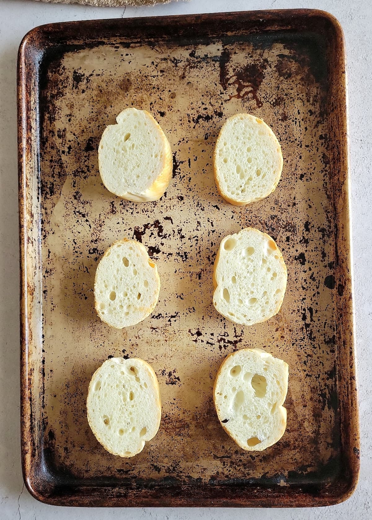 6 un-toasted baguette rounds on a baking sheet