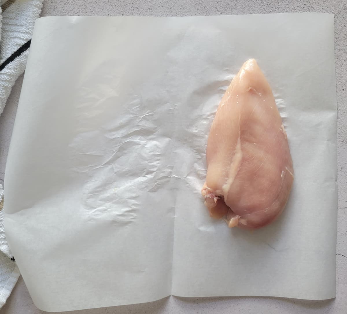 raw chicken breast on a piece of parchment paper