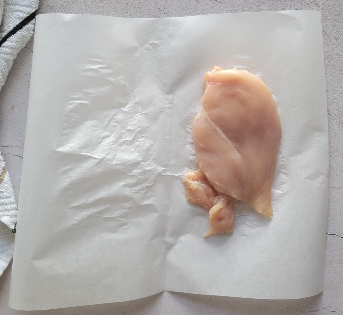 raw chicken breast on a piece of parchment paper