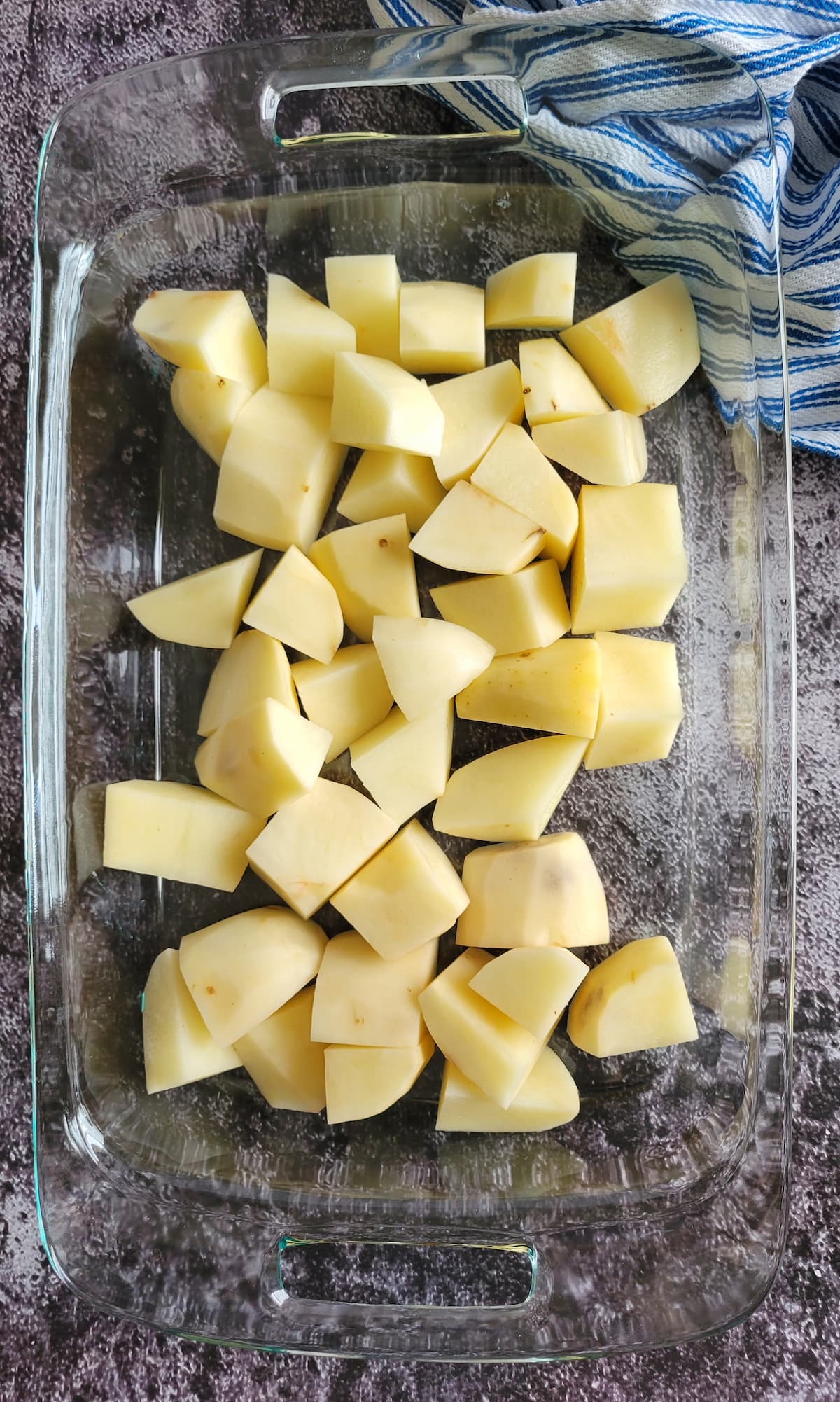 raw peeled potato chunks in a casserole dish