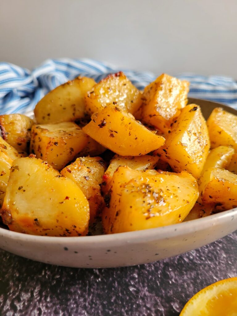 roasted and seasoned greek-style potatoes piled into a bowl.