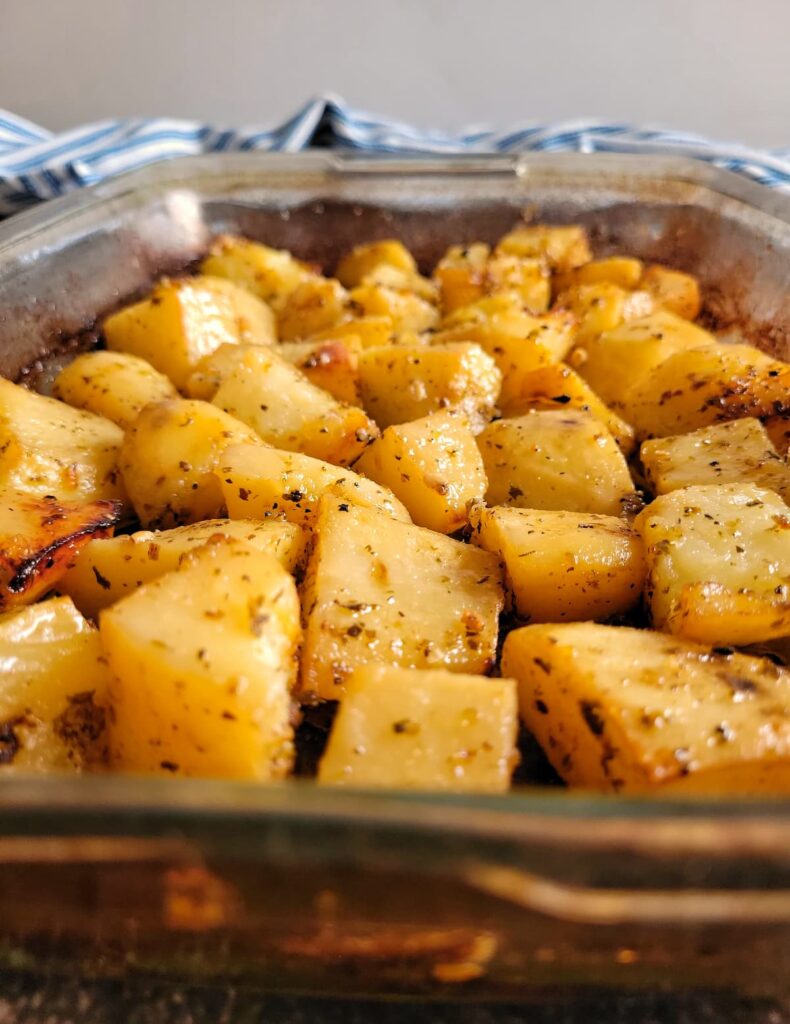 side view of cooked seasoned potato chunks in a casserole dish