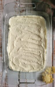 sour cream spread out in the bottom of a rectangular glass baking dish