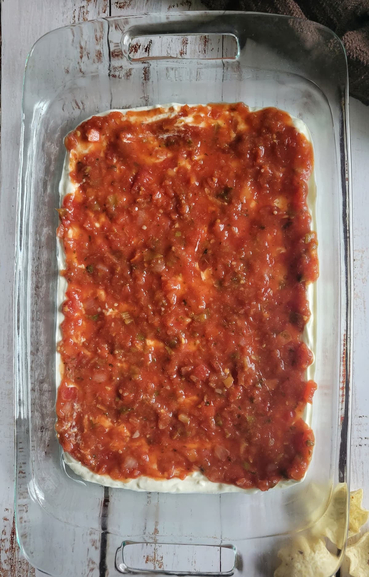 baking dish with a layer of salsa on top of a layer of sour cream
