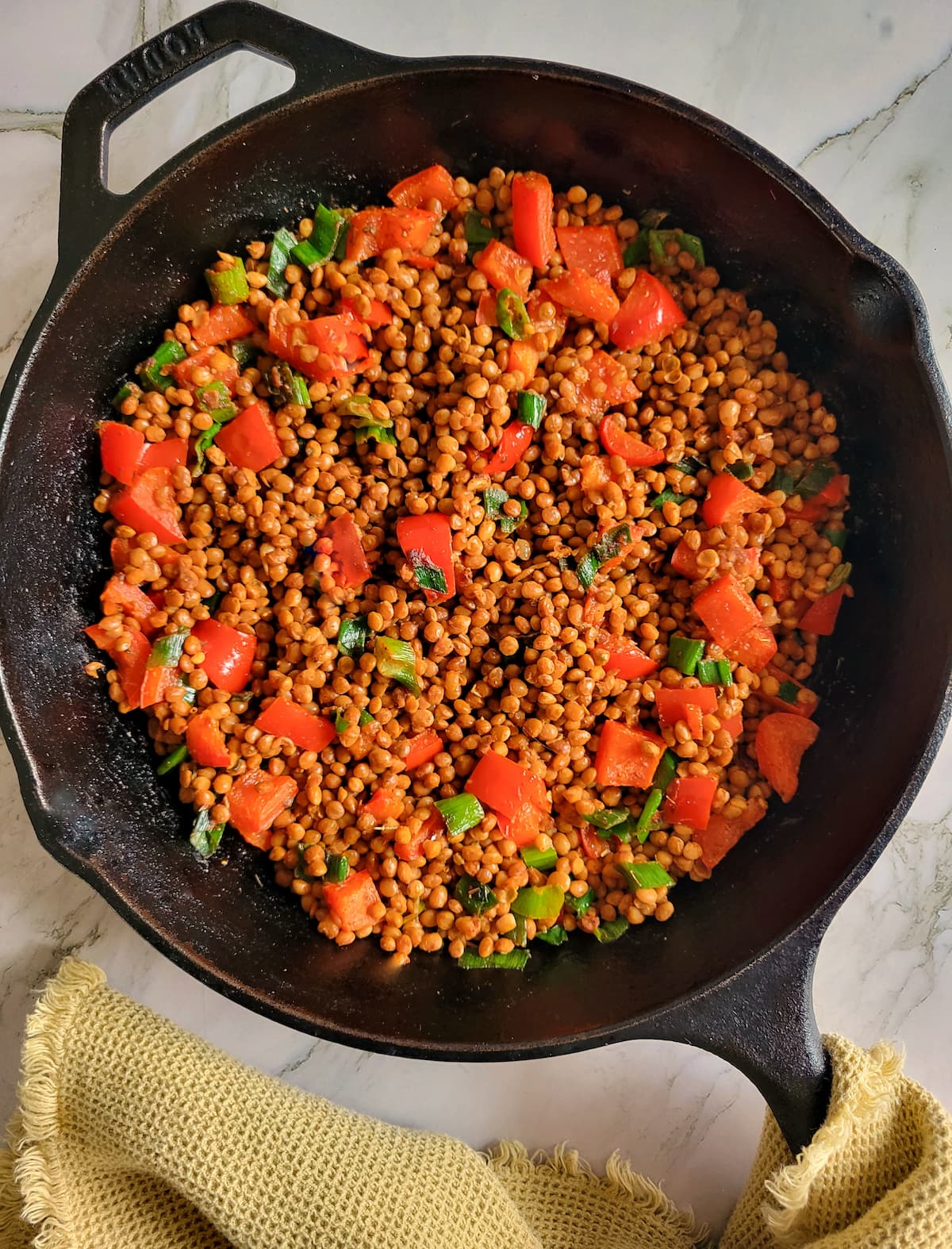 cast iron skillet with lentils, diced red peppers and green onions