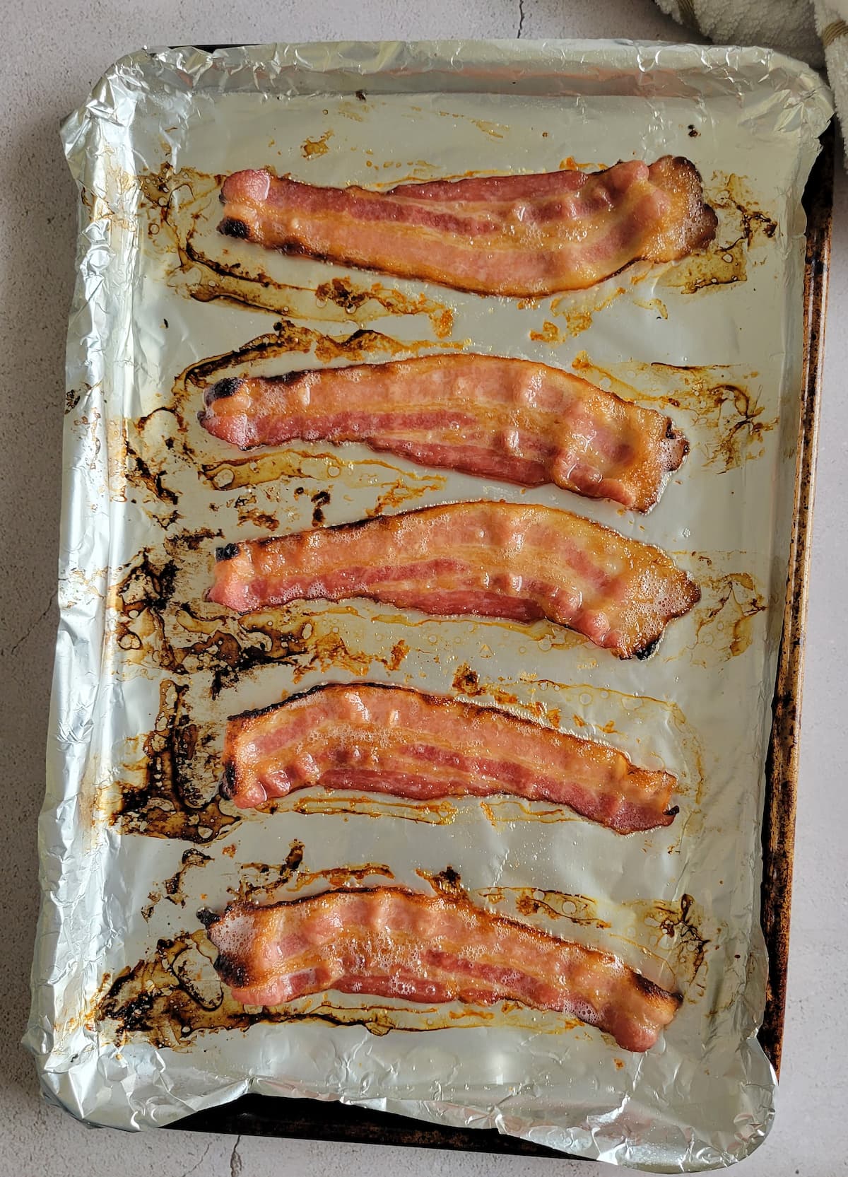 5 cooked strips of bacon on a foil rimmed baking sheet