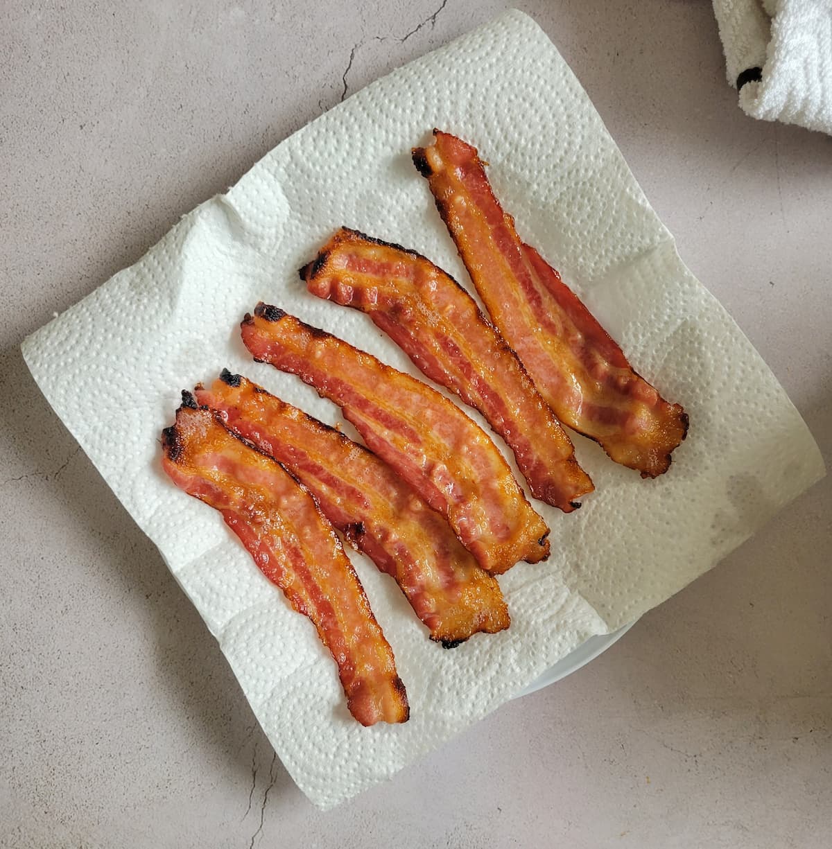 5 cooked strips of bacon on a paper towel lined plate