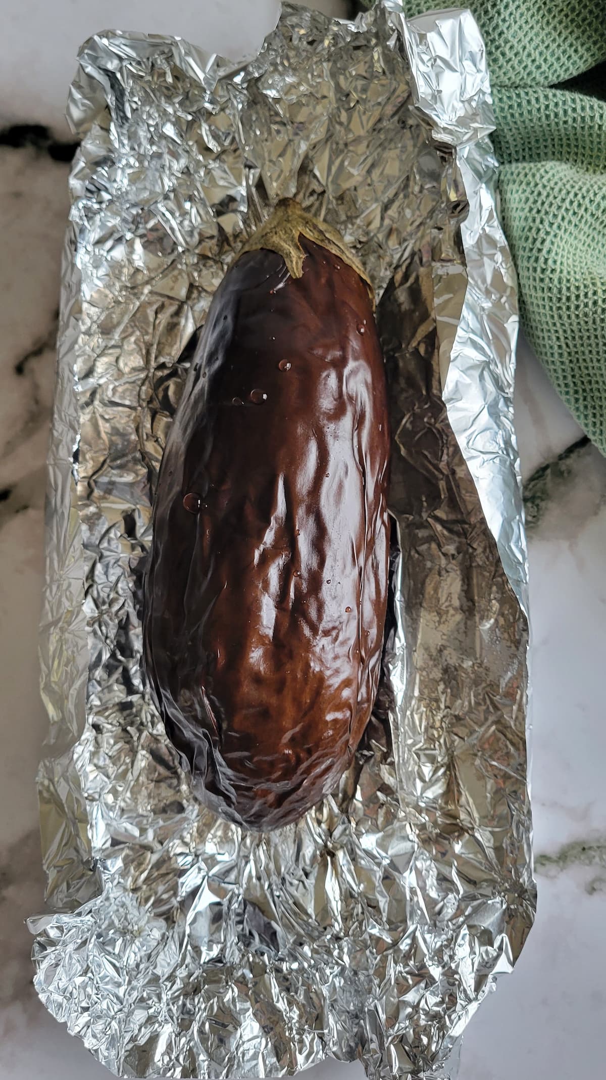 whole roasted unpeeled eggplant in a piece of foil