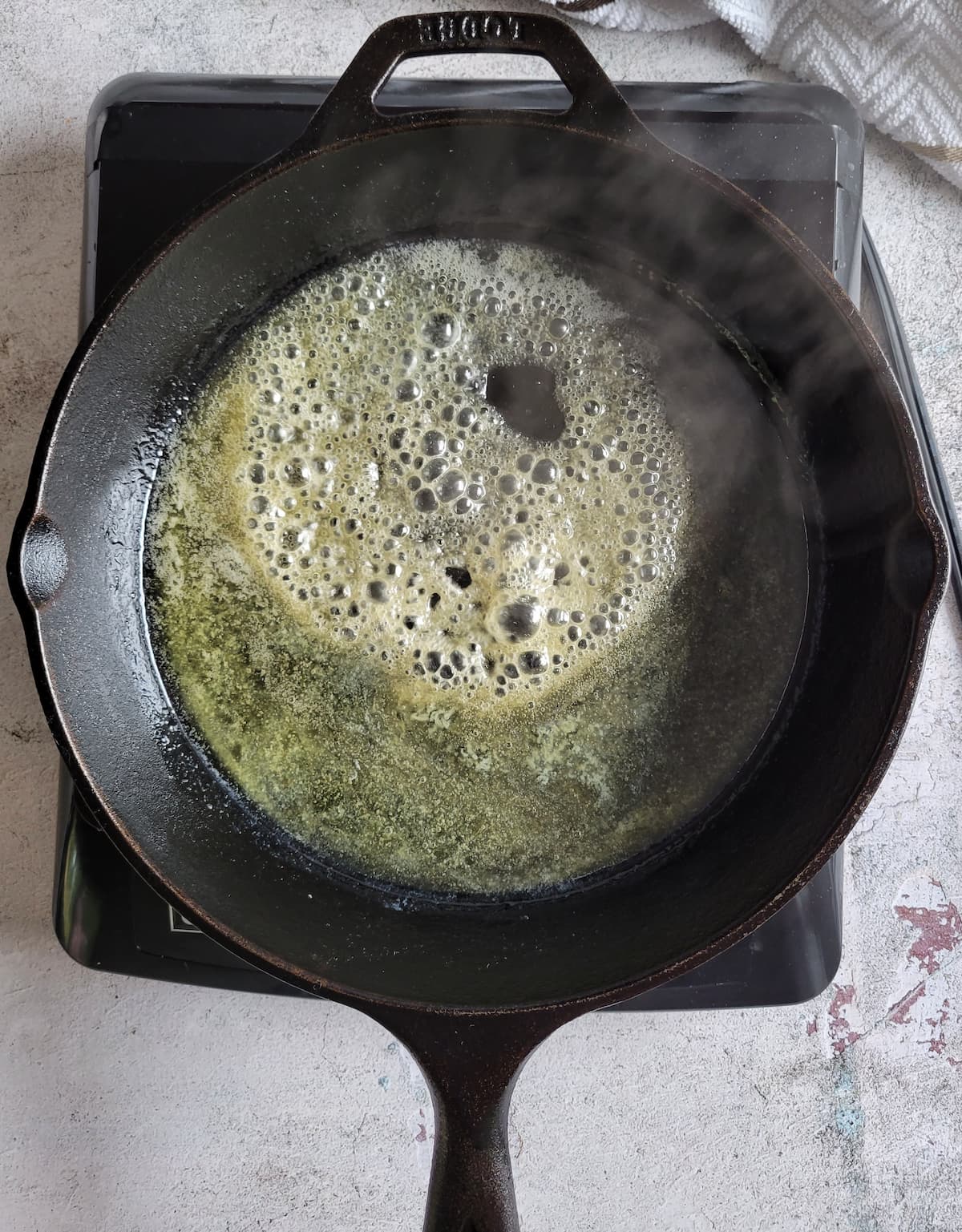 foaming melting butter in a cast iron skillet on a burner