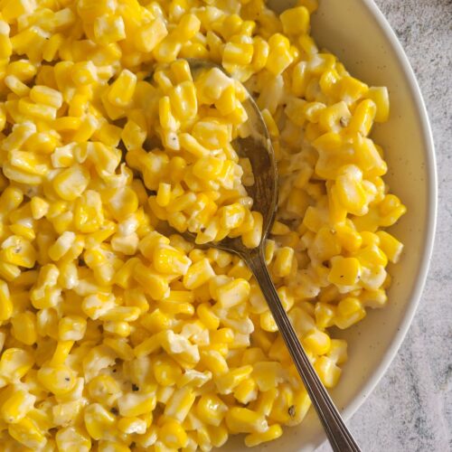 half a bowl of cream cheese with corn with a spoon in it