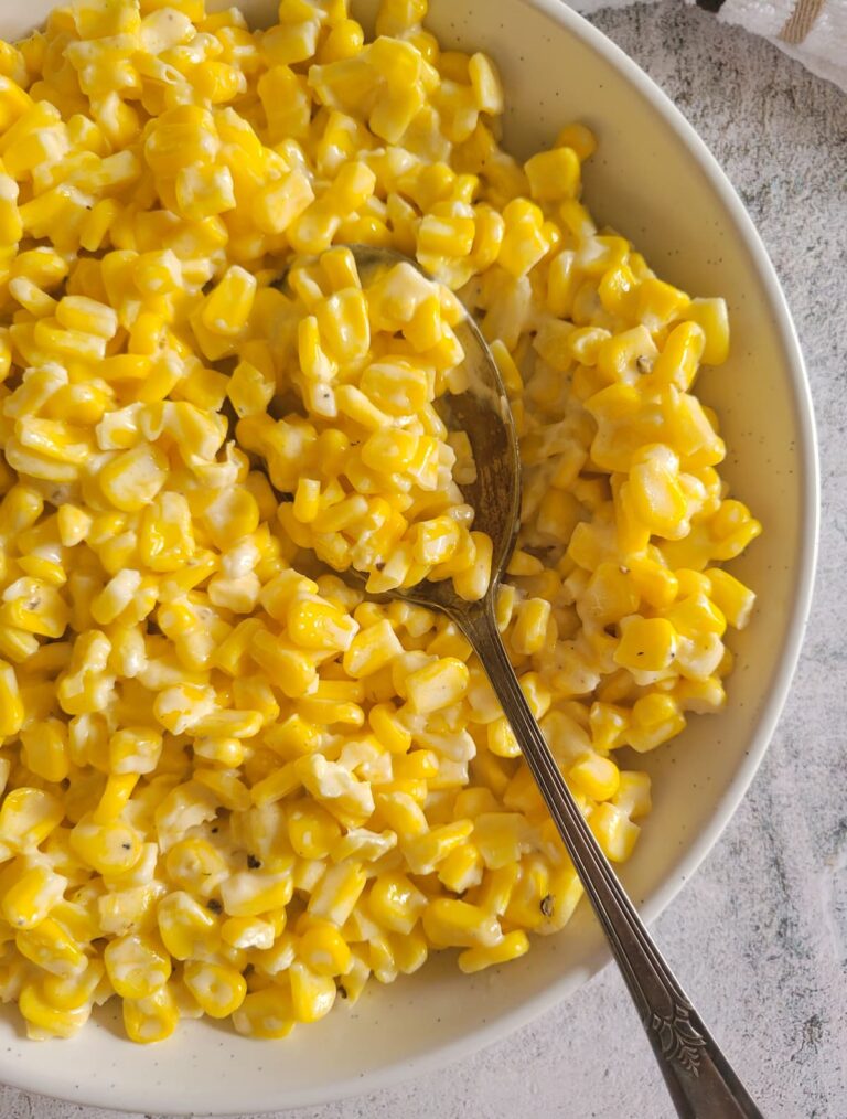 half a bowl of cream cheese with corn with a spoon in it