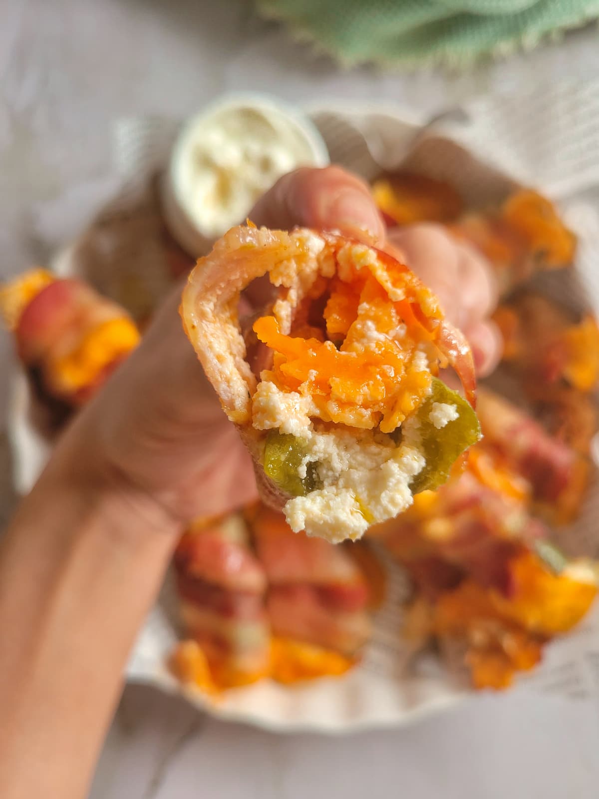 inside of a jalapeno popper wrapped in bacon over a plate of the rest of them