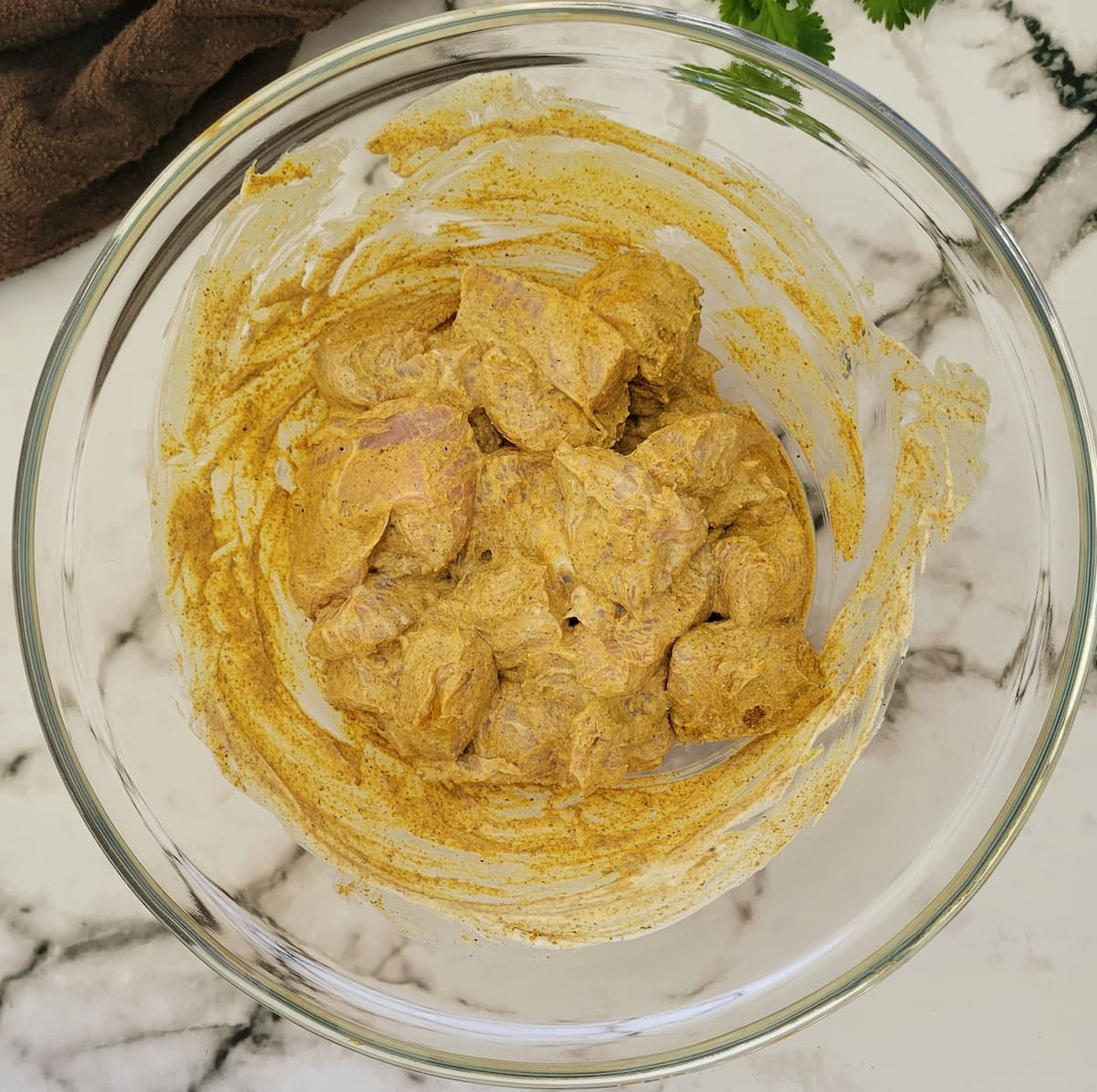 chicken pieces in a bowl marinating in greek yogurt and spices
