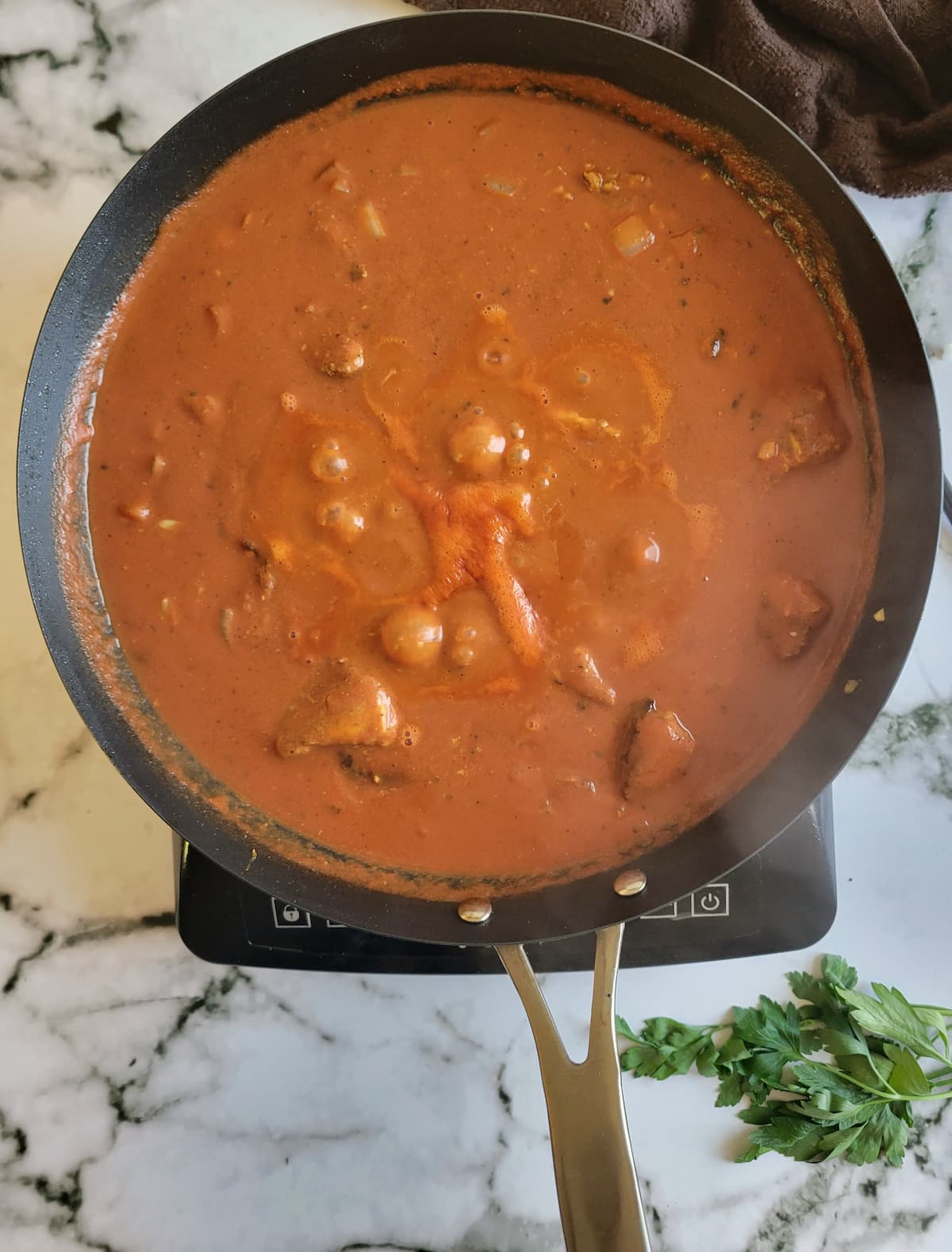 red sauce bubbling in a pan on a burner
