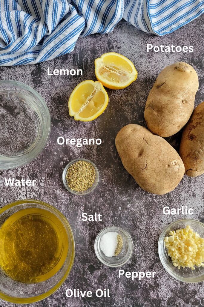 ingredients for roasted potatoes in oven - potatoes, lemon, oregano, water, olive oil, garlic, salt and pepper
