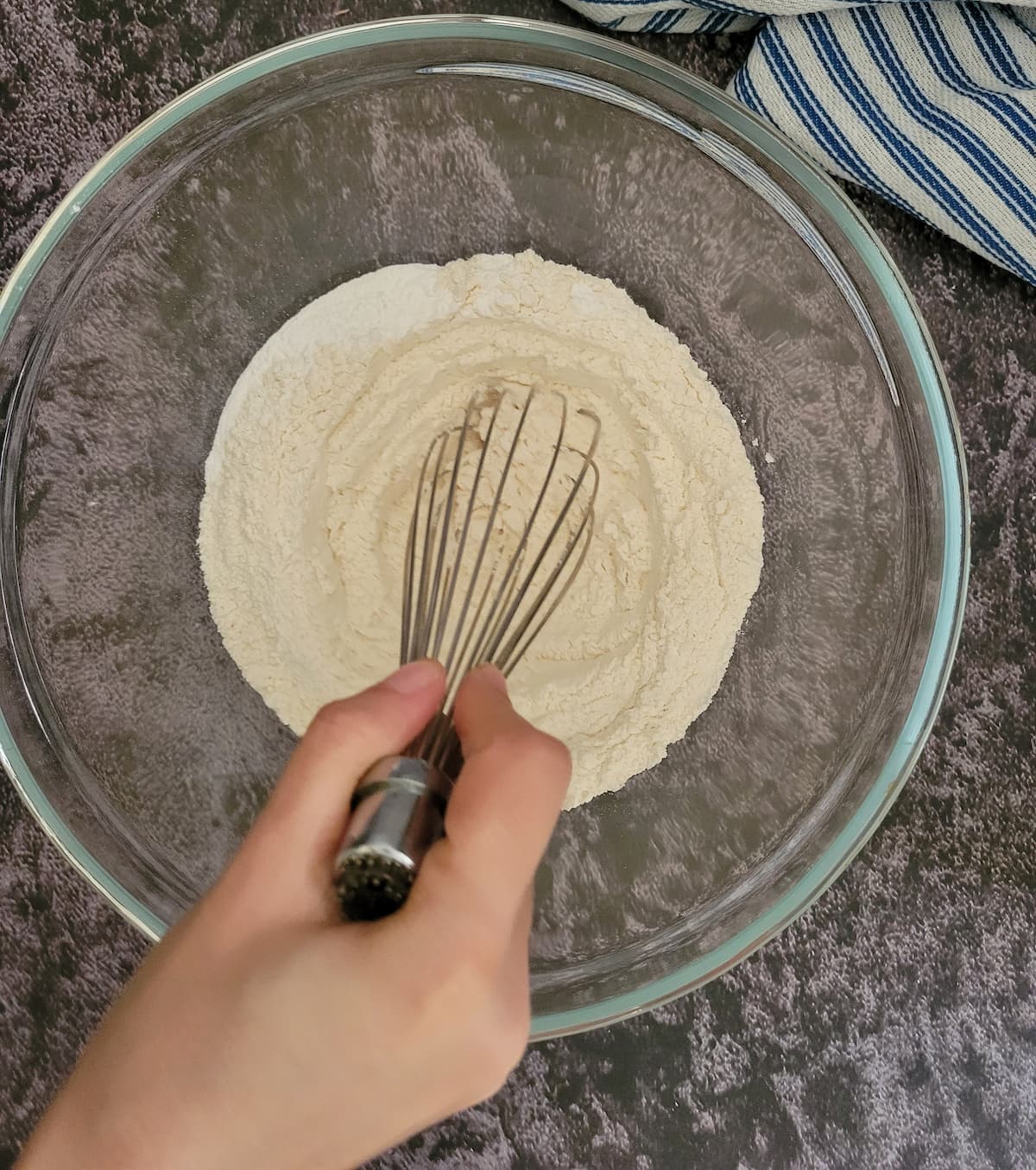 hand with a whisk in a bowl of self rising flour
