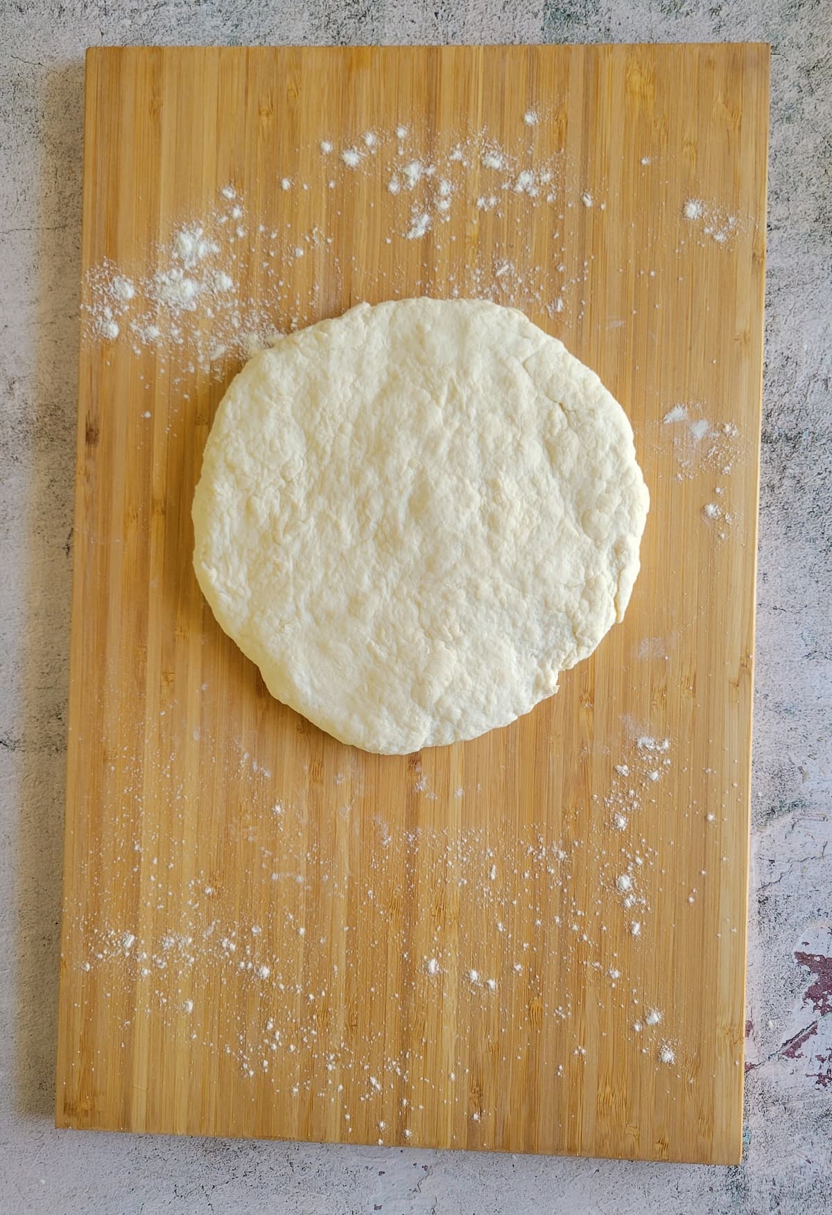 circular piece of dough on a floured cutting board