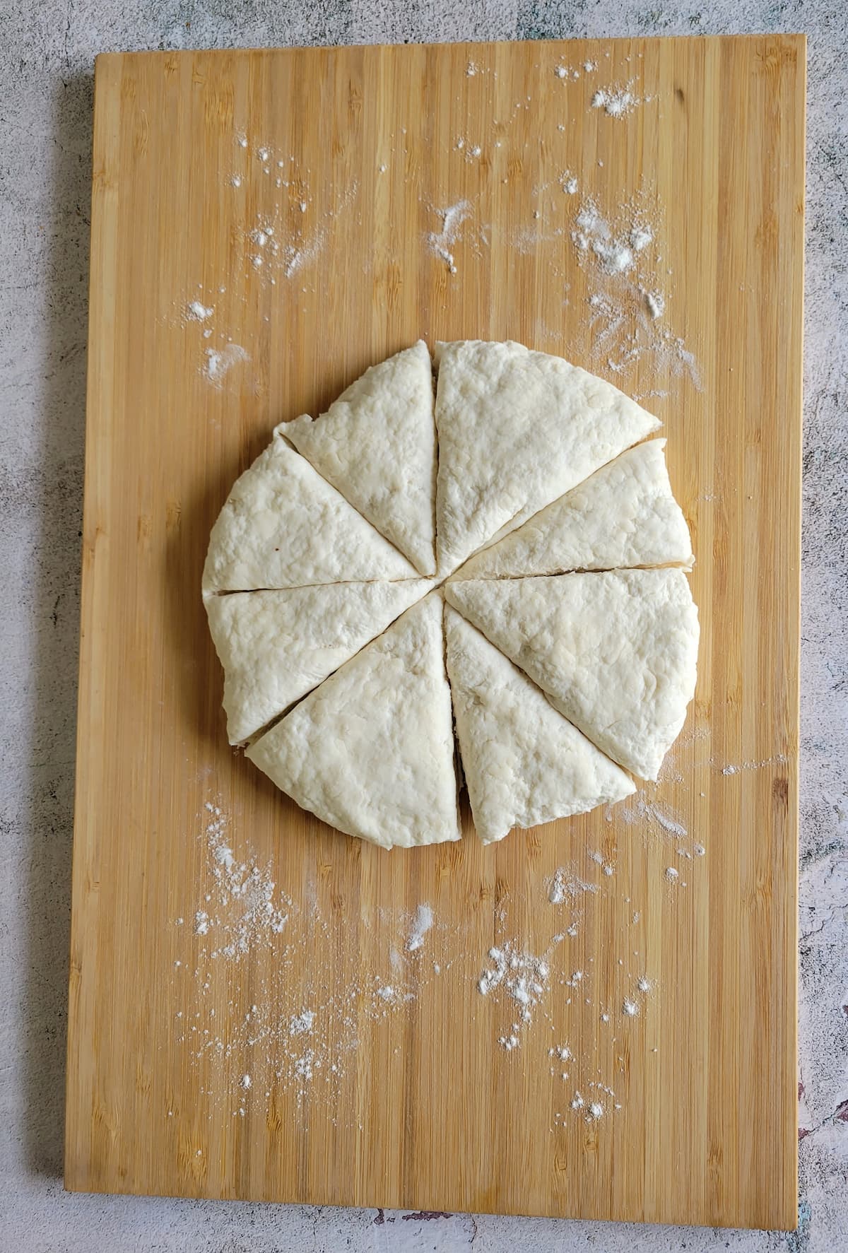 circular piece of dough cut into 8 triangles on a floured cutting board