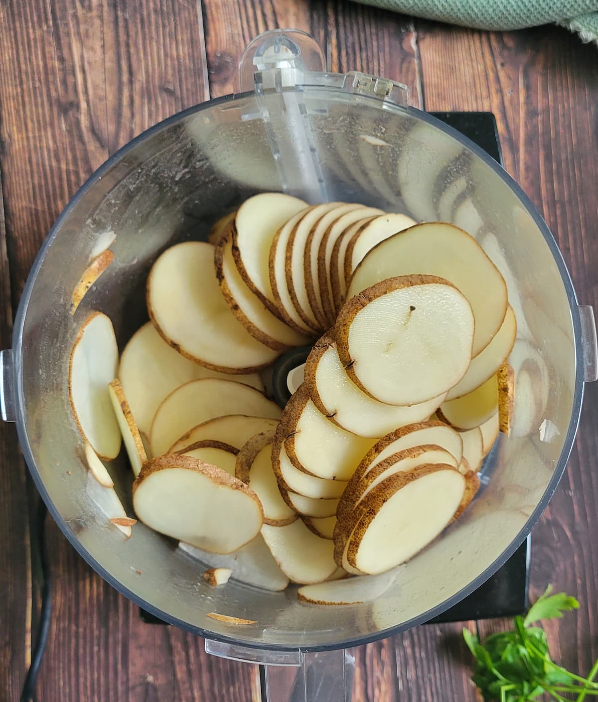 thinly sliced potatoes in the bottom of a food processor