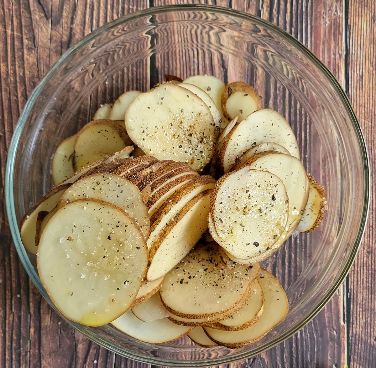 bowl of thinly sliced potatoes seasoned for salt and pepper