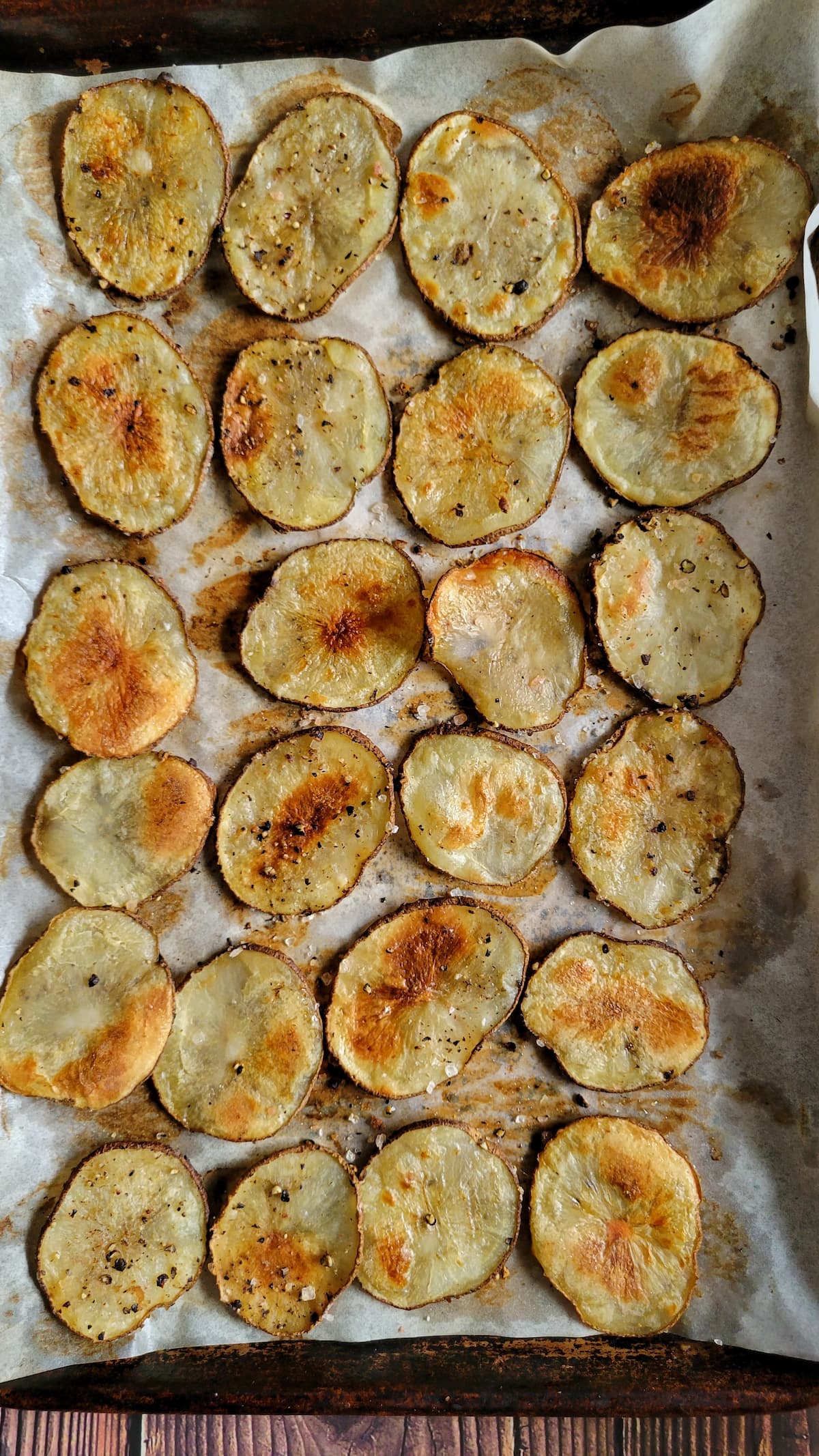 cooked potato slices in a single layer on a parchment lined baking sheet