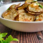 homemade potato chips in a bowl garnished with fresh chopped parsley