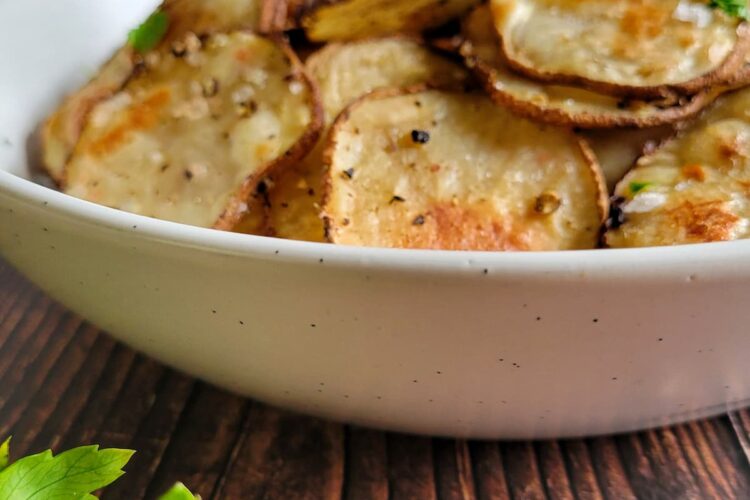 homemade potato chips in a bowl garnished with fresh chopped parsley