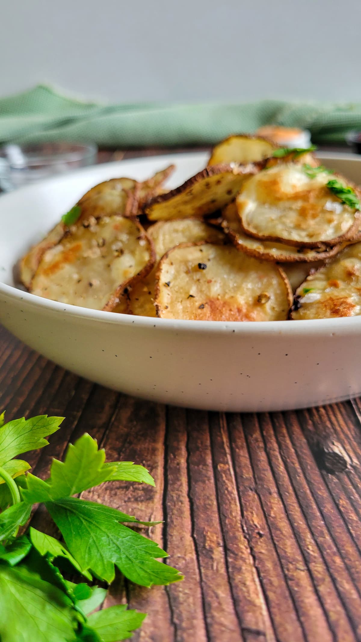 homemade potato chips in a bowl garnished with fresh chopped parsley