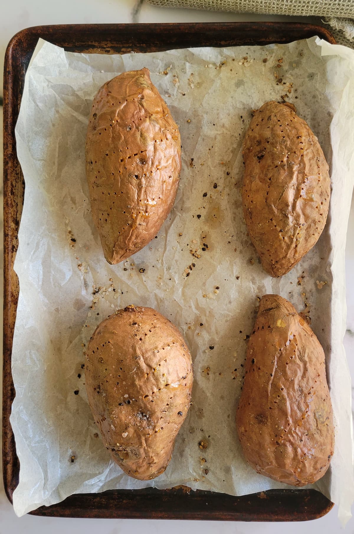 4 sweet potatoes on a parchment lined baking sheet