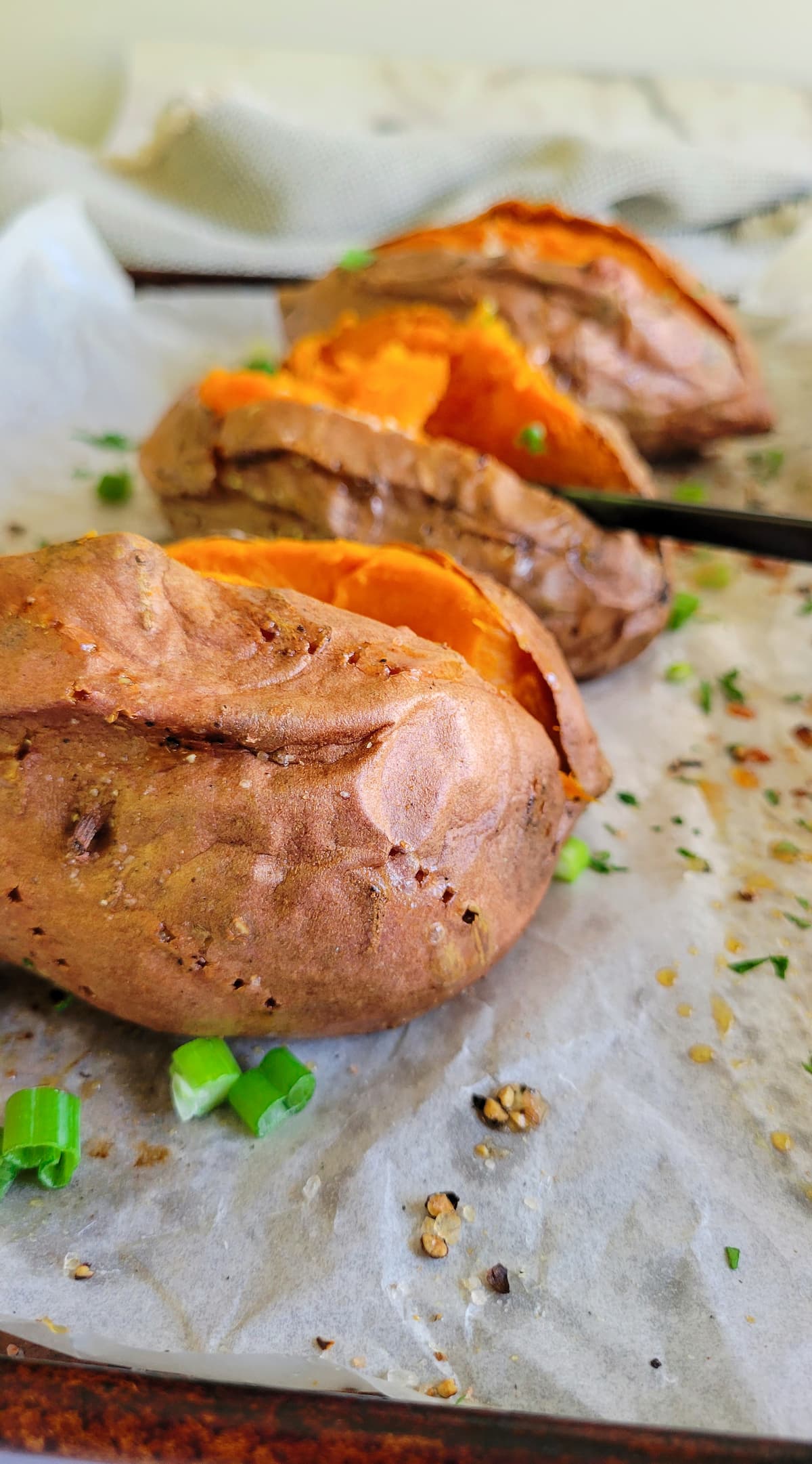 3 baked sweet potatoes cut open on a parchment lined baking sheet