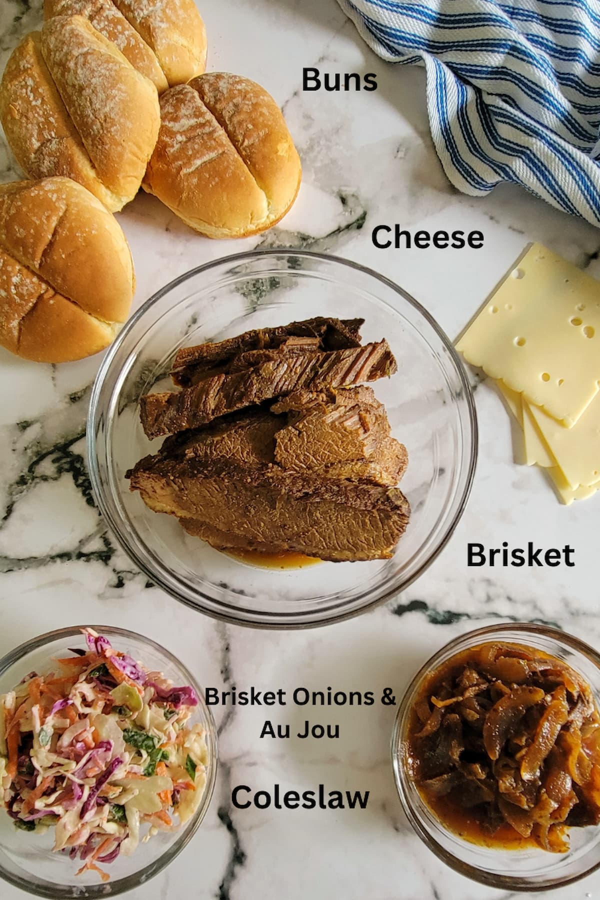 ingredients for brisket of beef sandwich - brisket, buns, cheese, coleslaw, onions and au jus