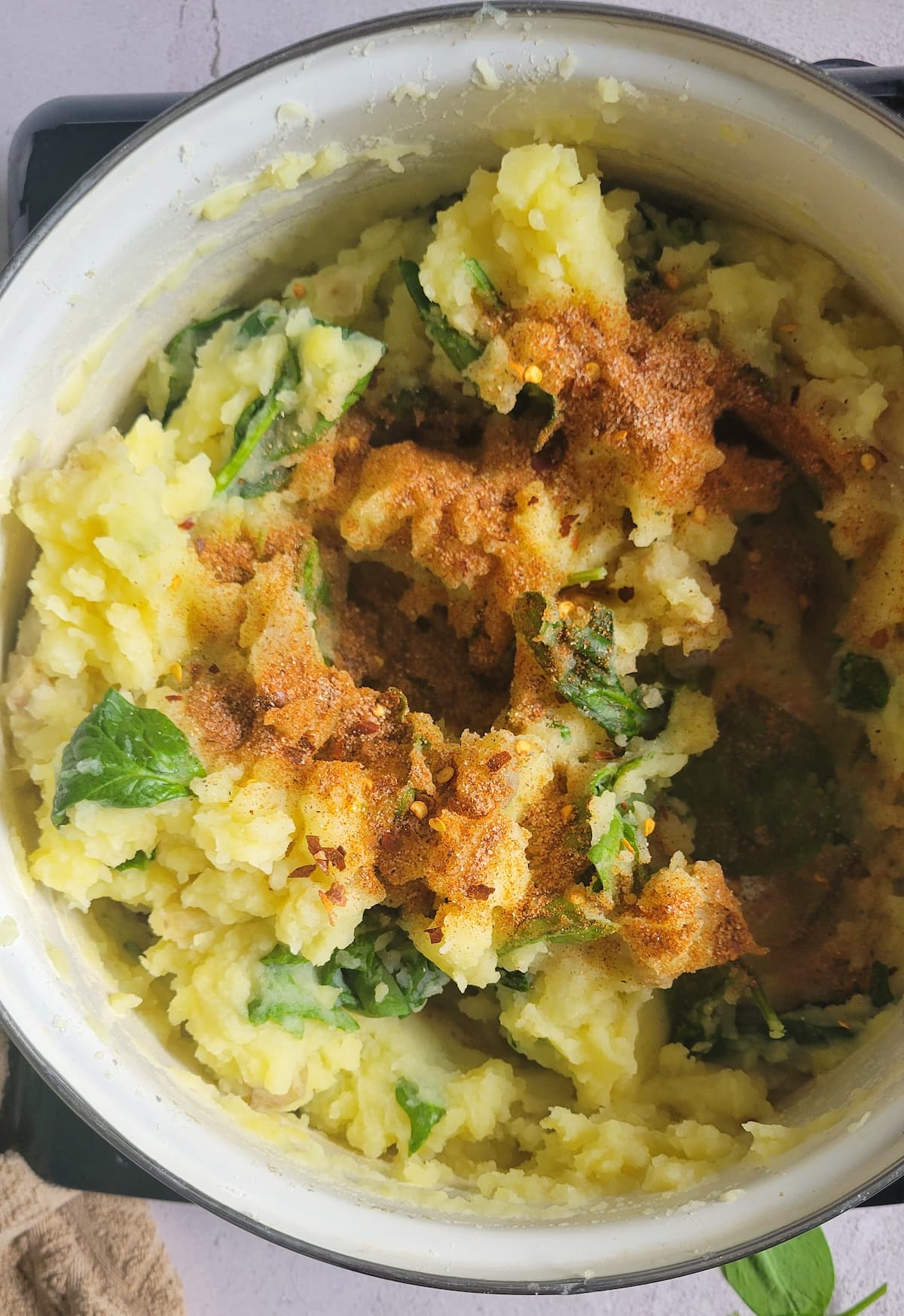 mashed potatoes and spinach topped with paprika in a pot