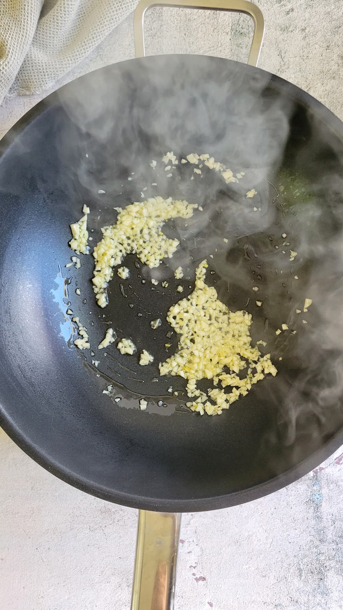 minced garlic sautéeing in a wok with oil