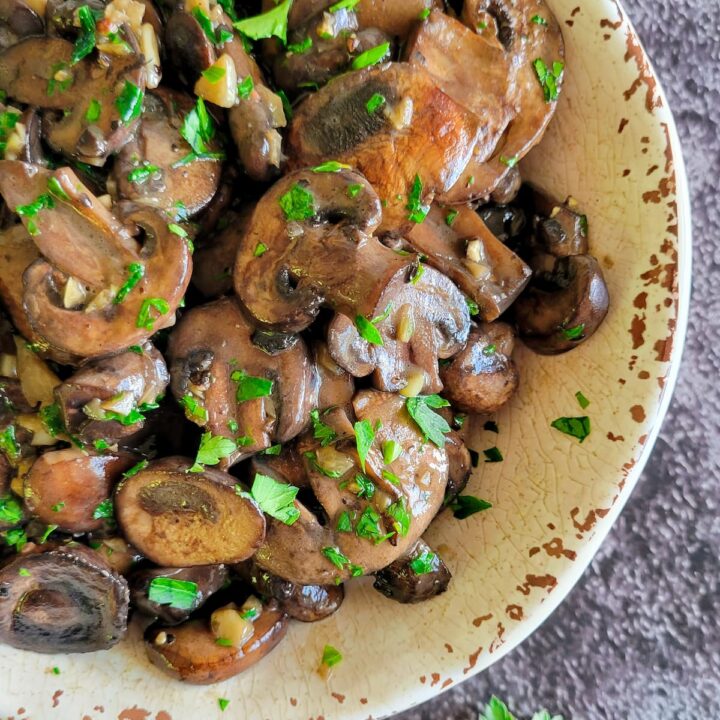 a bowl of sauteed mushrooms garnished with fresh chopped parsley