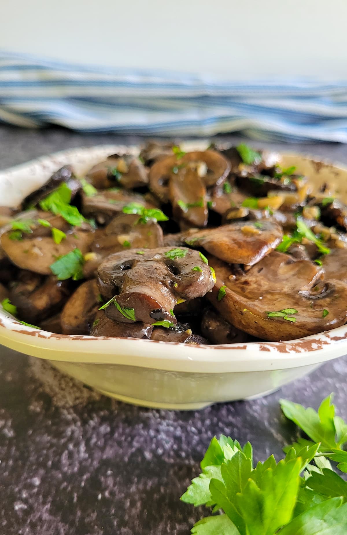 side view of a bowl of sauteed mushrooms garnished with fresh chopped parsley