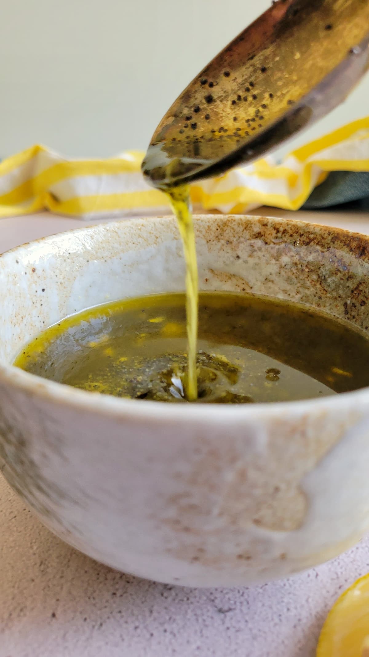 lemon poppy seed dressing falling off a spoon into a bowl with the rest of it