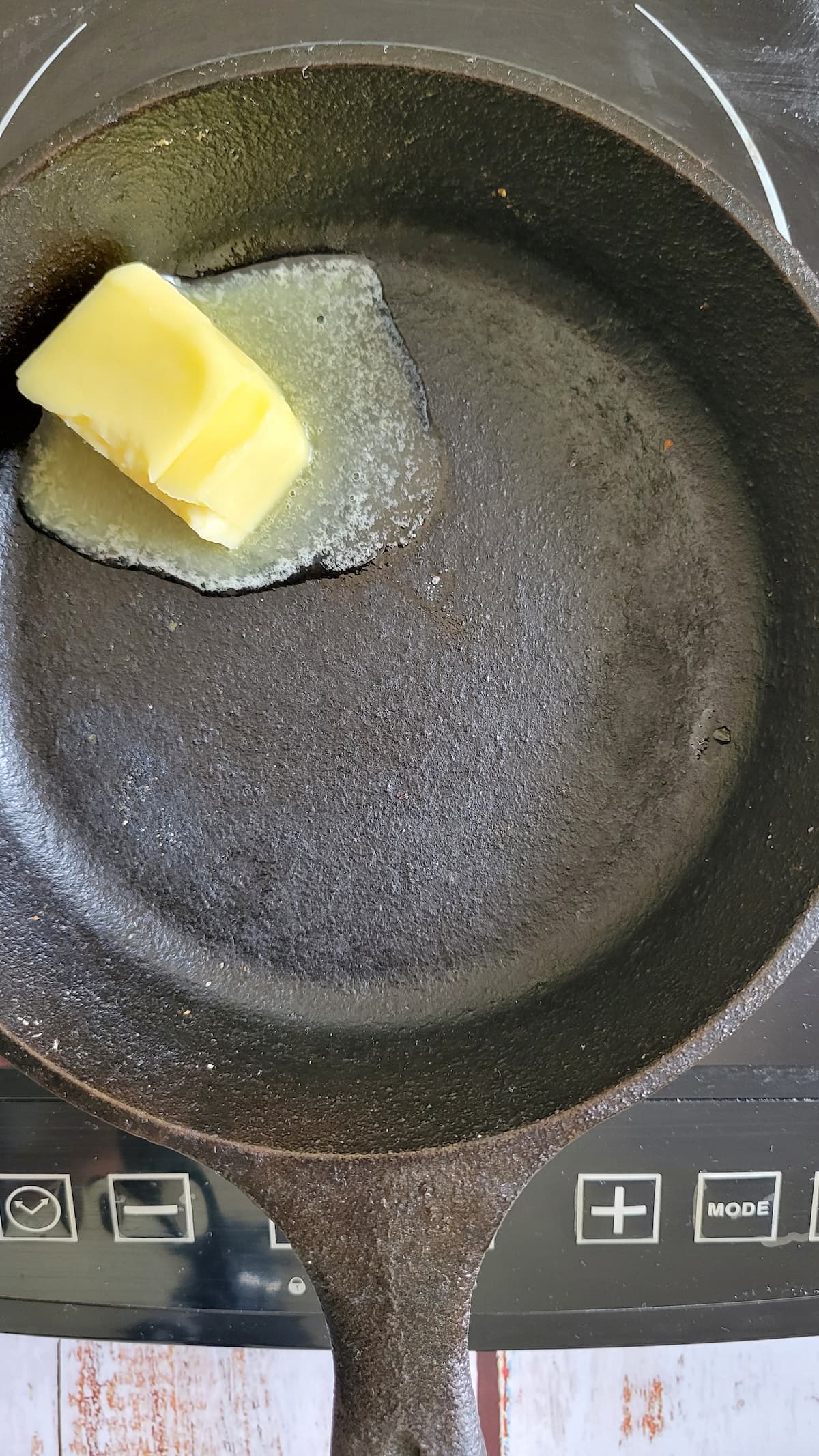 butter melting in a cast iron skillet on a burner