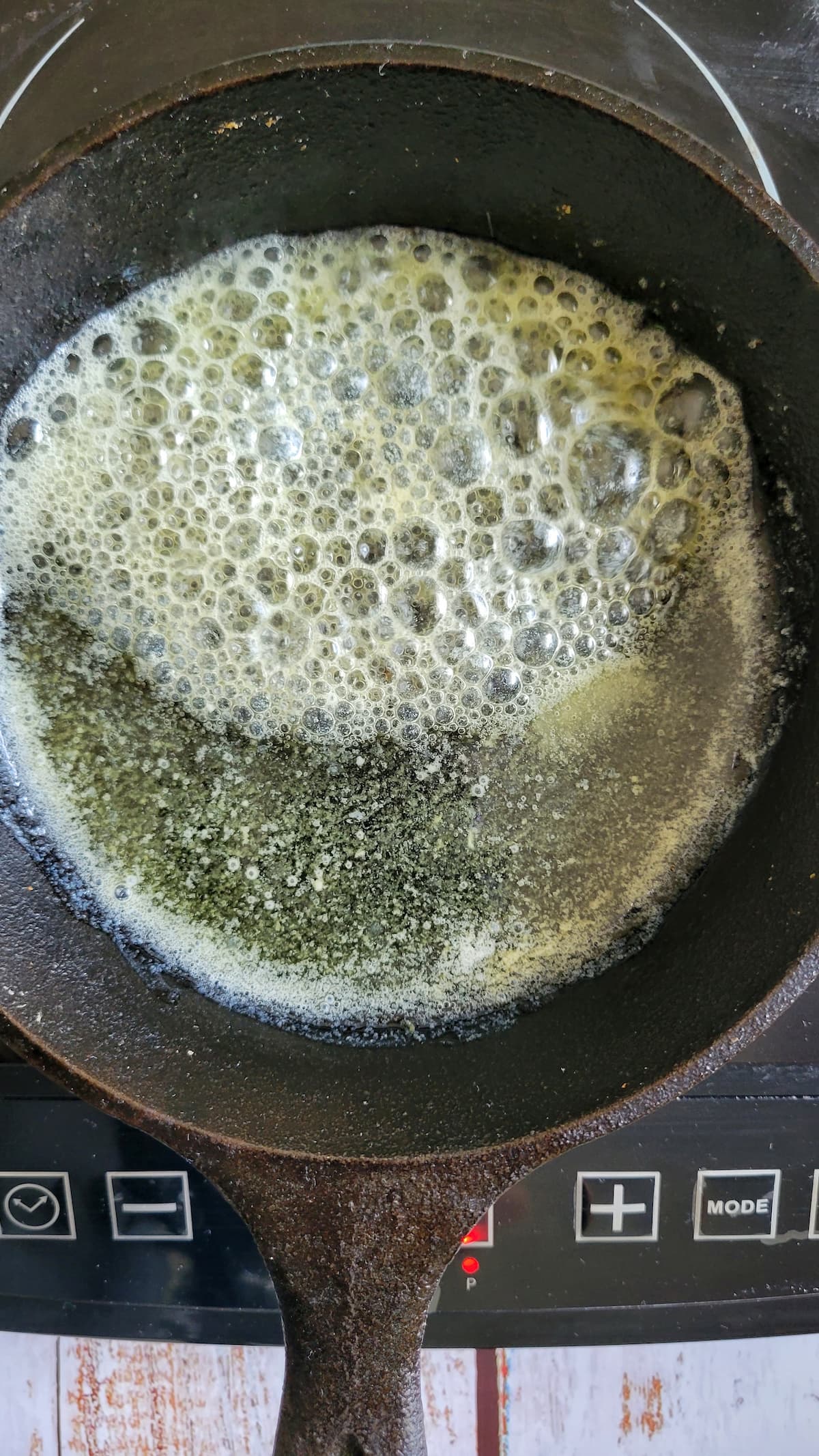 melted butter frothing in a cast iron skillet on a burner