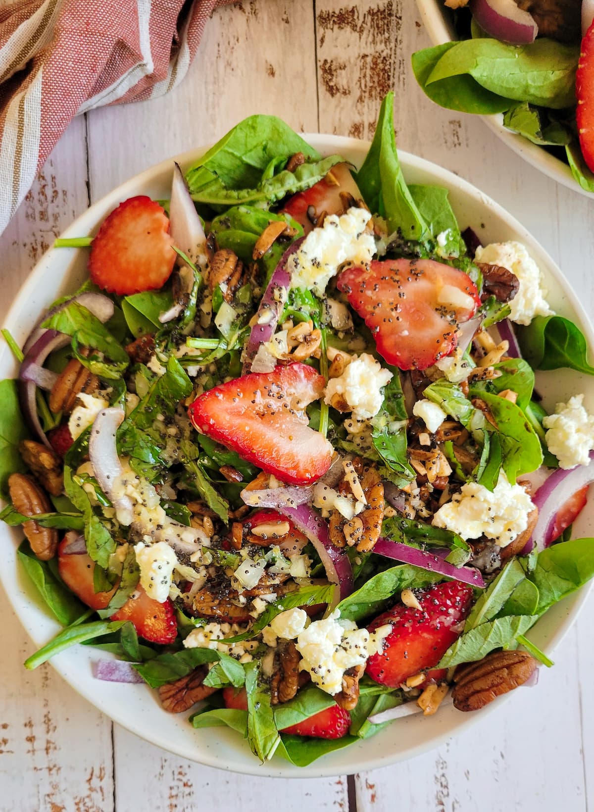 salad with spinach, sliced strawberries, goat cheese, red onions, pecans and poppy seed dressing