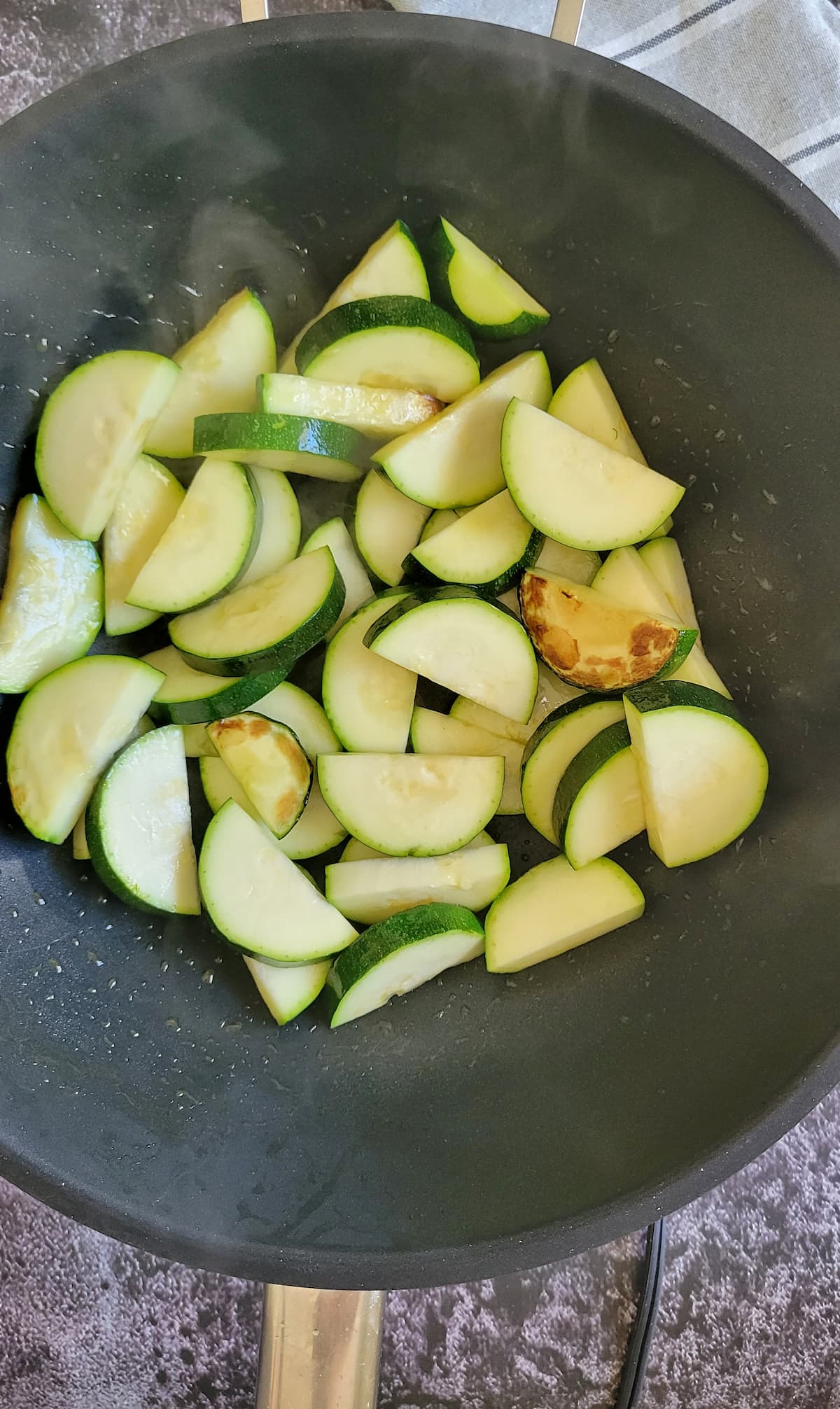 half moon zucchini slices cooking in a wok