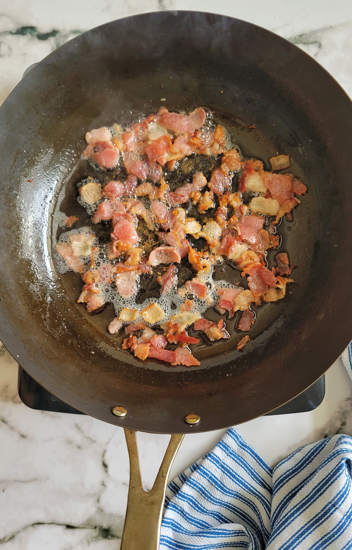 crumbled bacon cooking in a skillet