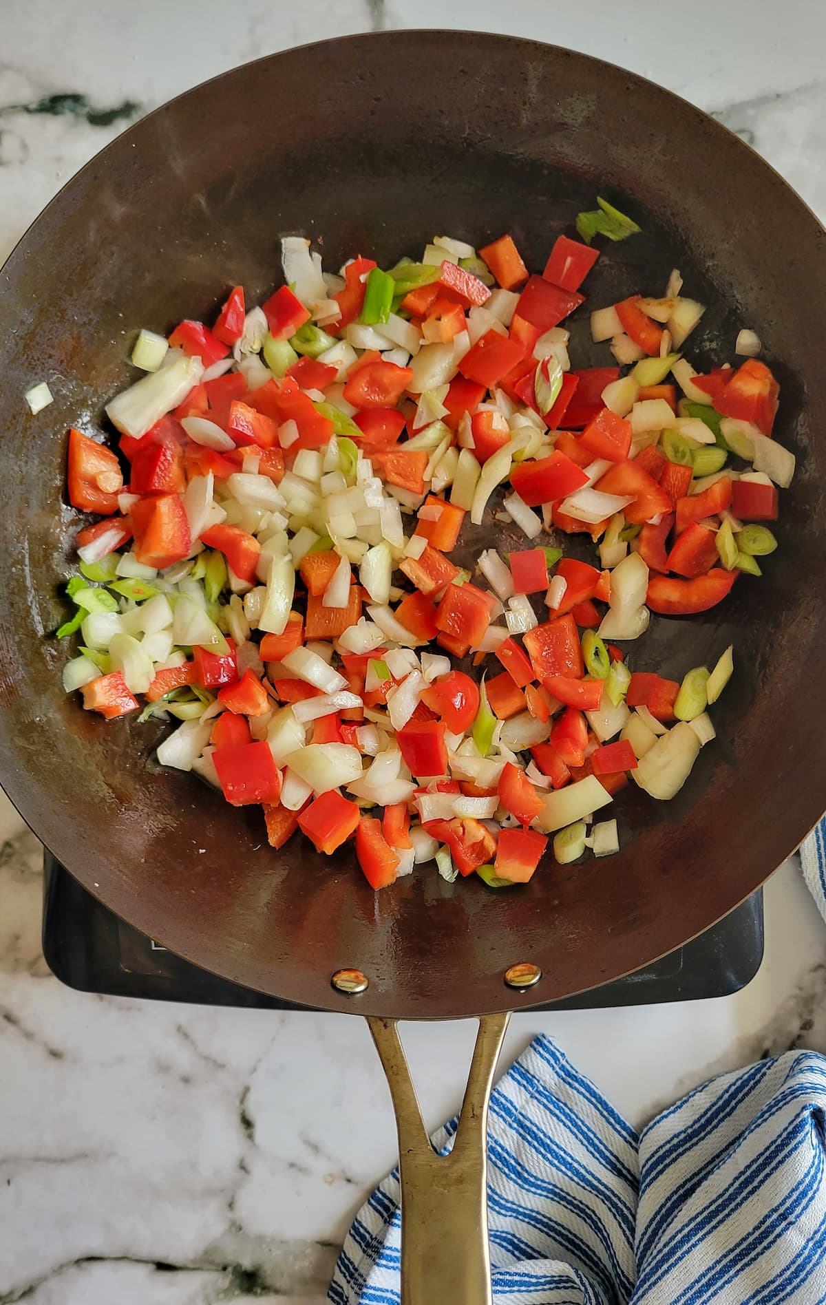 diced white and green onion and red bell pepper in a skillet