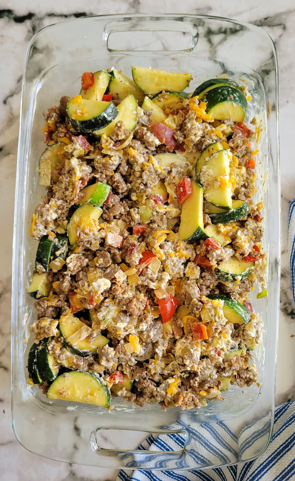 cooked italian sausage, red peppers, zucchini and cheese in a casserole dish