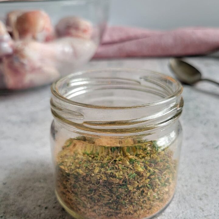 jar of spices, bowl of raw chicken drumsticks in the background