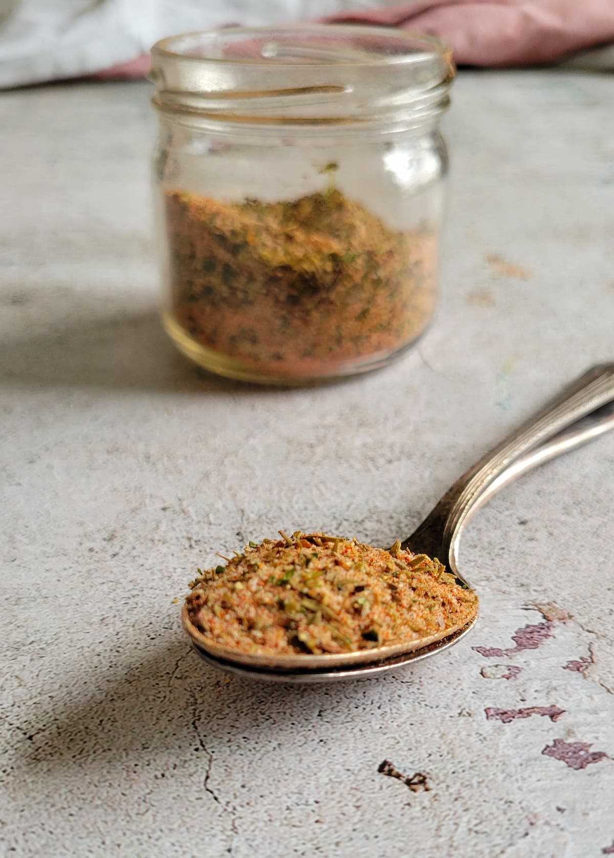 spices on a spoon in front of a jar with more
